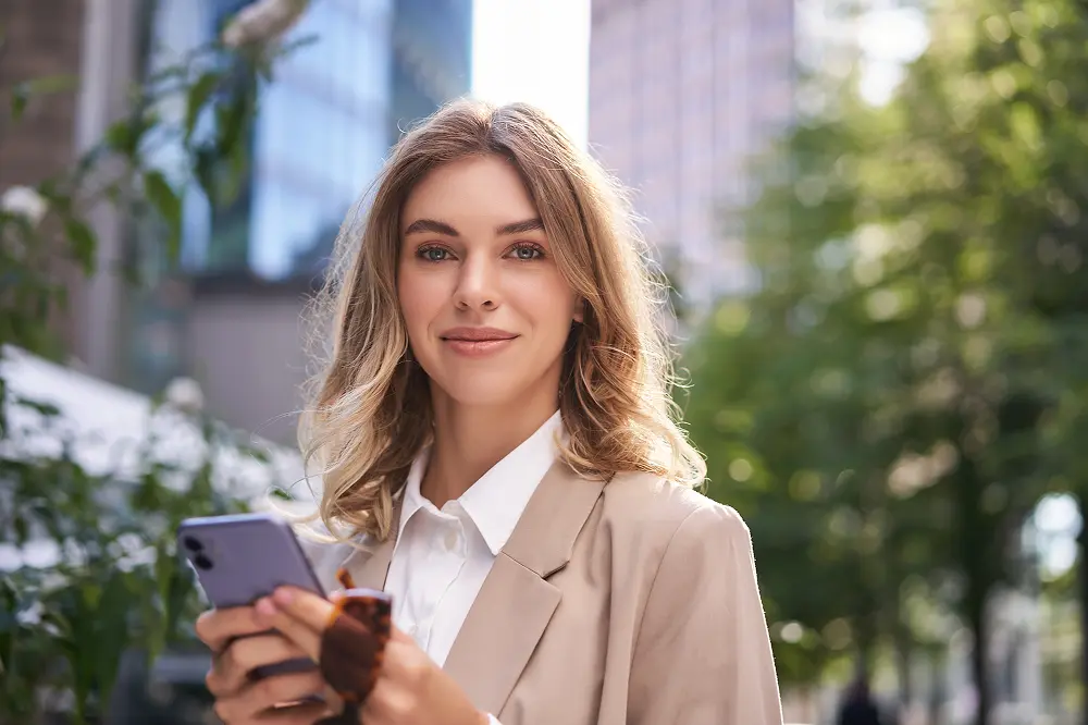 close-up-portrait-corporate-woman-young-intern-walks-street-office-holds-mobile-phone-texts 1.webp